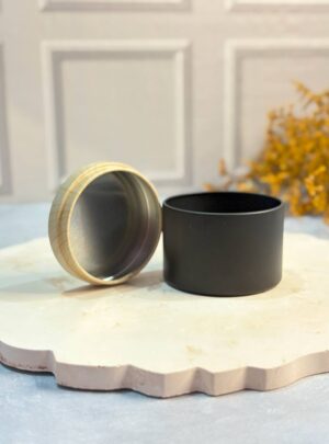 LATA NEGRA 120 ML CON TAPA COLOR MADERA Medidas: 6 cm de diámetro x 5 cm de alto. Práctica y elegante, esta lata metálica en acabado negro mate con tapa color madera es ideal para la creación de velas artesanales. Su diseño moderno combina resistencia y estilo, ofreciendo un envase seguro y atractivo. La tapa tipo madera le da un toque cálido y natural, convirtiéndola en una opción perfecta para velas de colección, detalles personalizados o regalos especiales. Ideal para quienes buscan un empaque minimalista y con carácter distintivo. NOTA: La tapa es de lata no es madera real.
