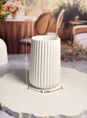 Nuestro Florero de Líneas de Yeso de 10 cm de alto y 6 cm de ancho es una pieza que destaca por su ritmo visual y su funcionalidad mejorada.