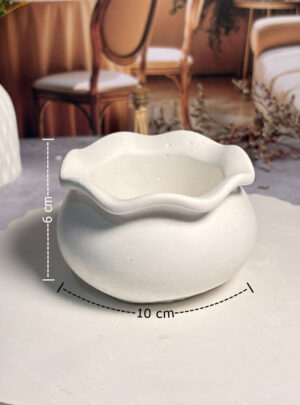 Nuestra Vasija Ondulada de Yeso de 10 cm de ancho y 6 cm de alto es una pieza escultórica funcional que rompe con la rigidez de las formas tradicionales.